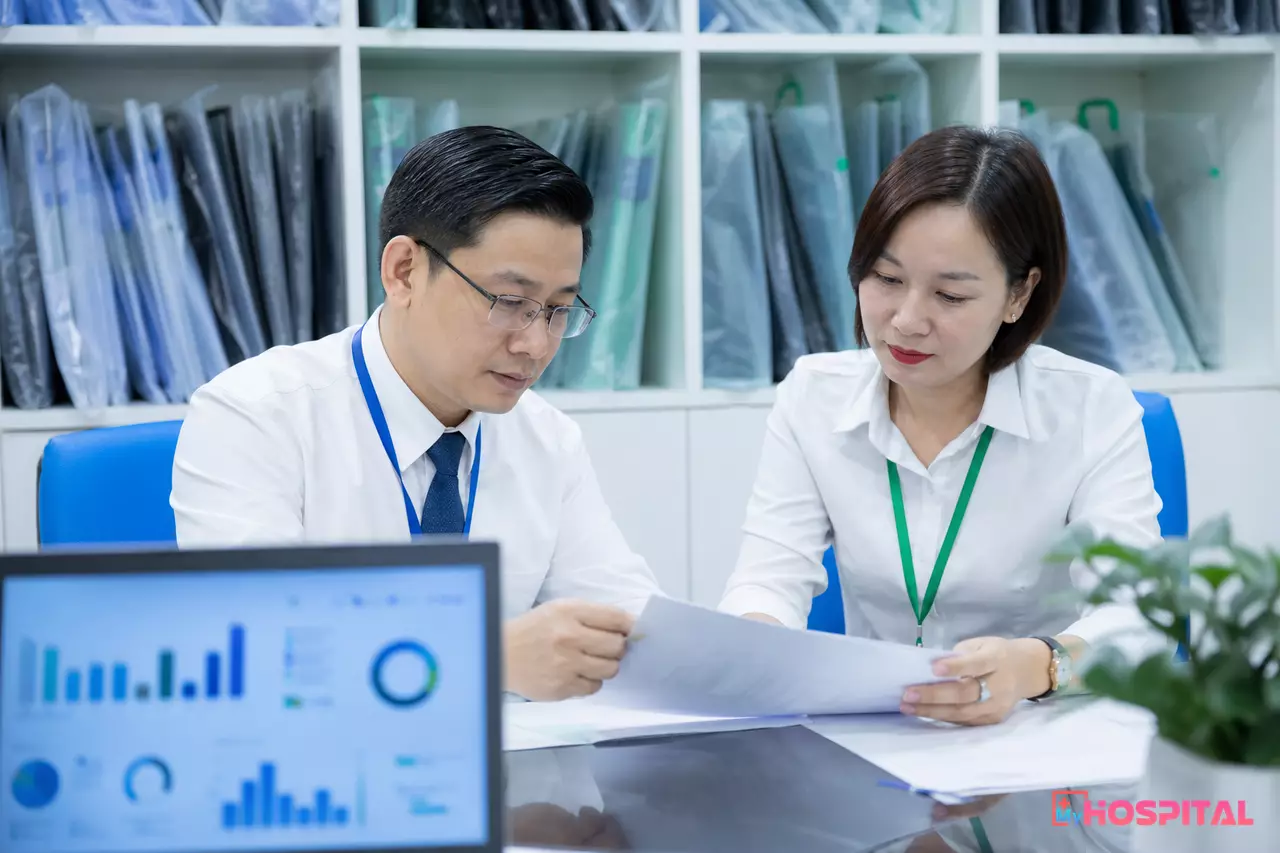 Giám đốc và kế toán trưởng bệnh viện xem bảng tính chi phí in phim X-quang trong phòng họp