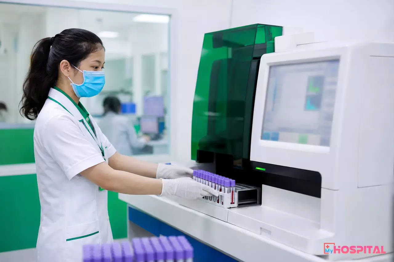 Kỹ thuật viên đặt khay ống máu vào máy phân tích huyết học trong khoa xét nghiệm