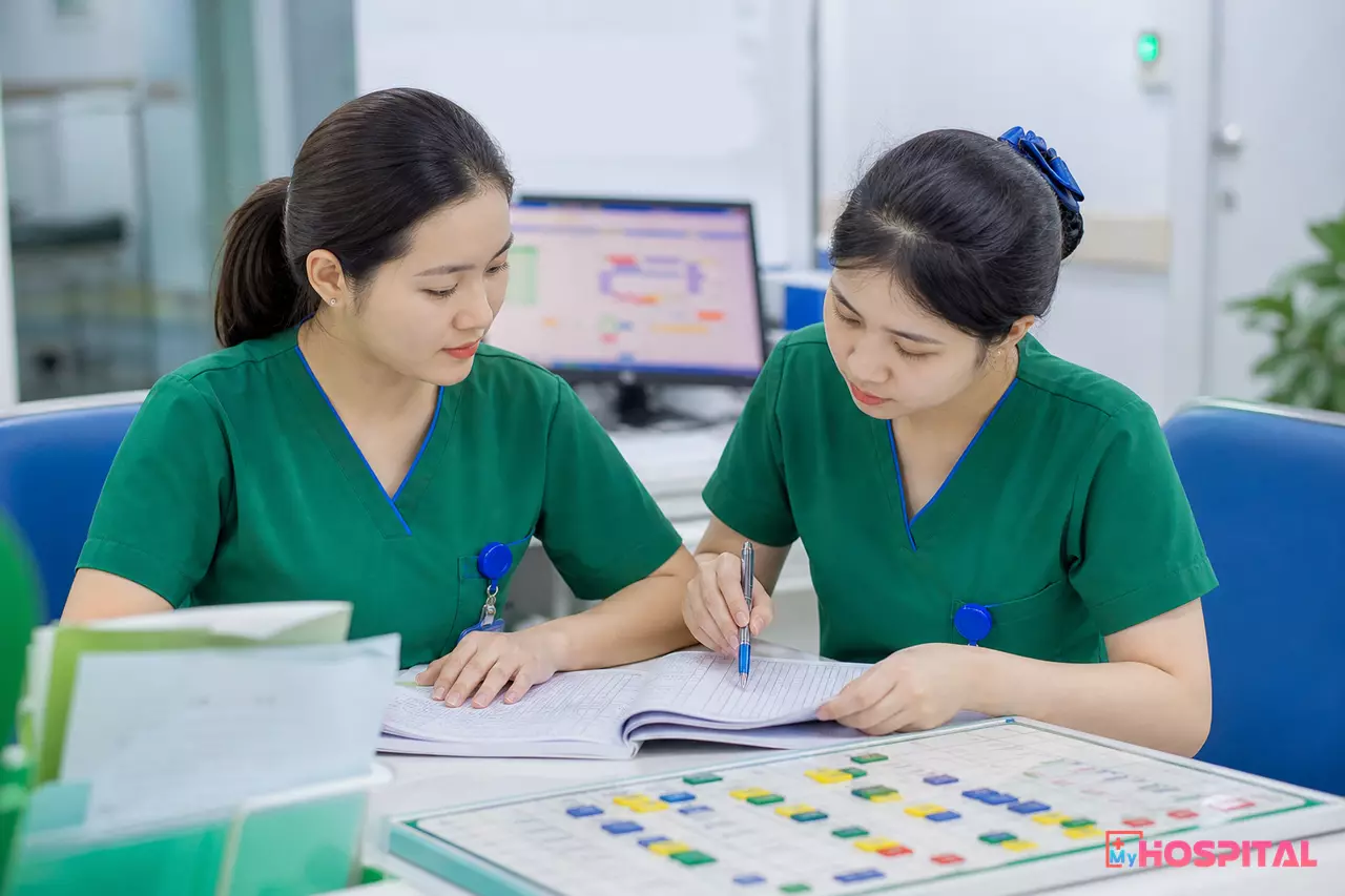 Hai điều dưỡng đối chiếu sổ thống kê giấy cuối ngày để tính số ngày điều trị của khoa