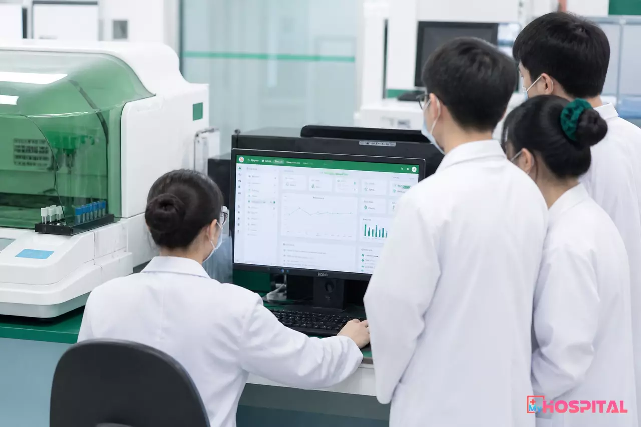 Kỹ thuật viên và người hướng dẫn trước màn hình LIS trong phòng xét nghiệm