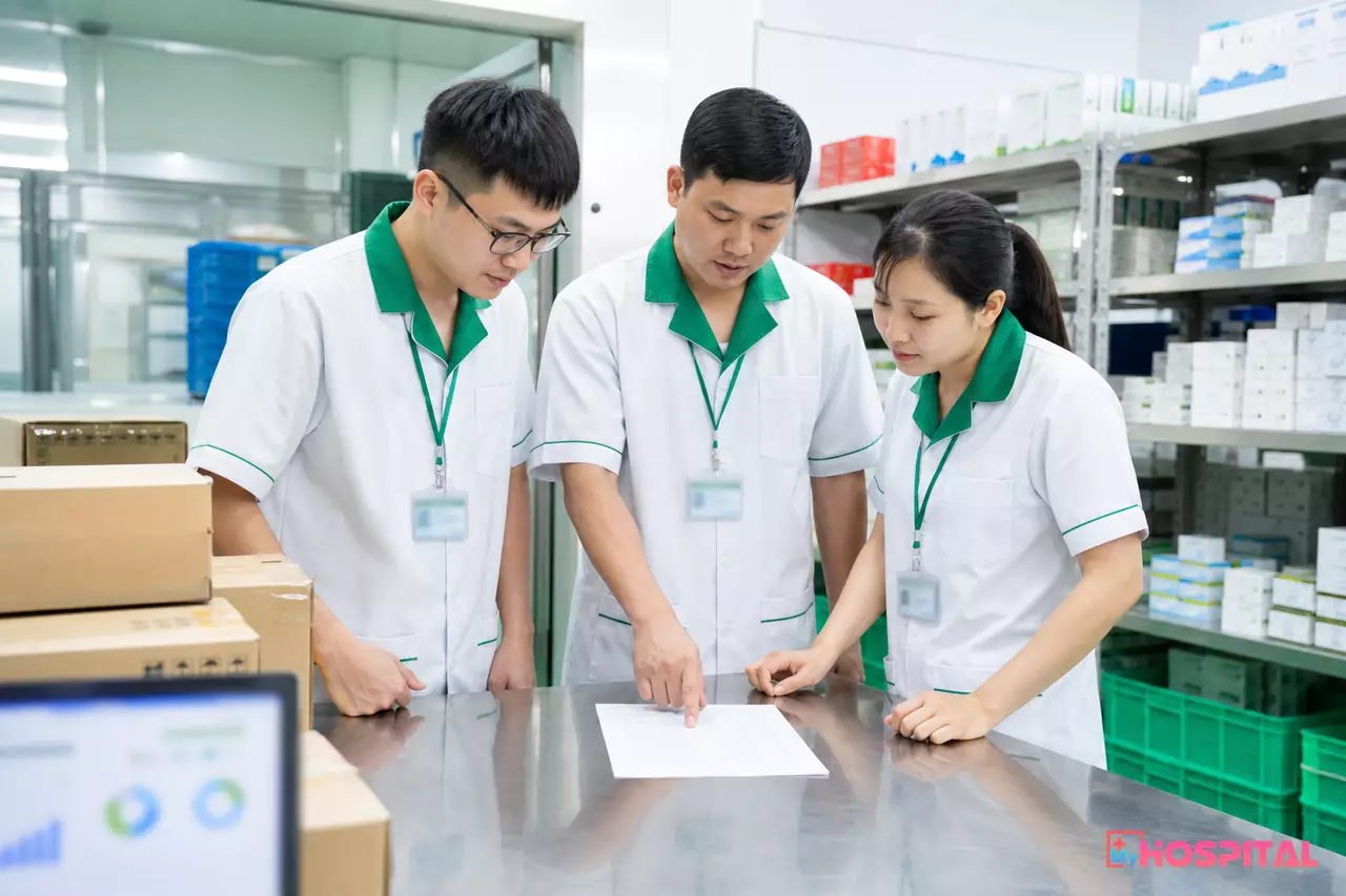 Ba nhân viên kho dược bệnh viện cùng đối chiếu phiếu nhập kho trước khi ký xác nhận