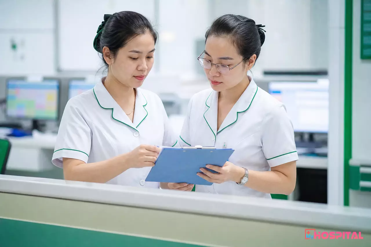 Hai điều dưỡng đối chiếu danh sách người bệnh tại quầy điều dưỡng khi giao ca