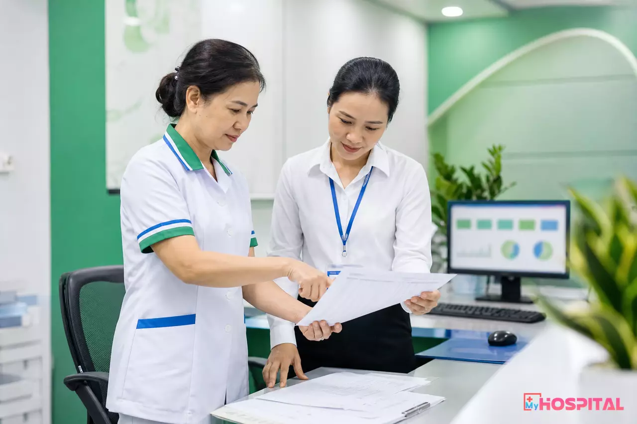 Điều dưỡng trưởng khoa và kế toán viện phí đối chiếu bảng kê dịch vụ in trong phòng hành chính khoa