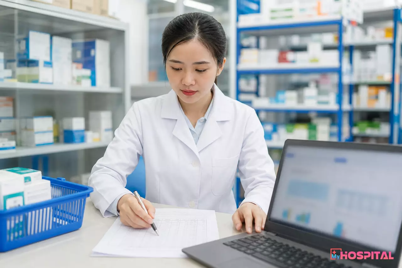 Dược sĩ đối chiếu số liệu kiểm kê với báo cáo tồn kho trên máy tính