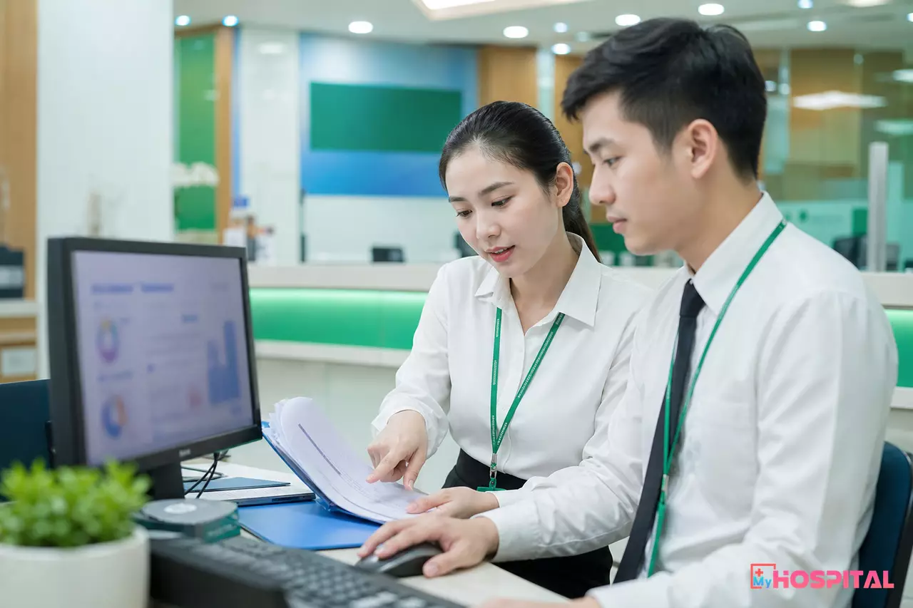 Kế toán viện phí đối chiếu báo cáo BHYT giữa bản in và máy tính tại quầy thu ngân
