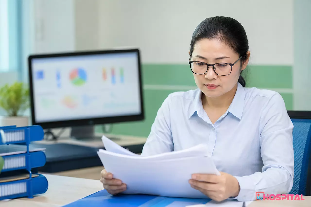 Kế toán trưởng viện phí kiểm tra nhật ký thao tác gộp hồ sơ người bệnh trên máy tính tại phòng làm việc