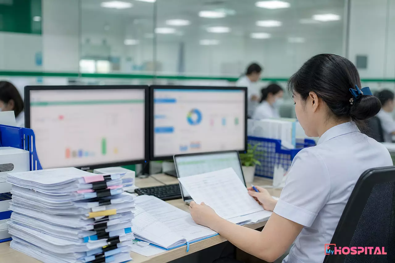 Nhân viên thống kê đối chiếu số liệu từ nhiều phần mềm và bảng kê in trong phòng hành chính bệnh viện