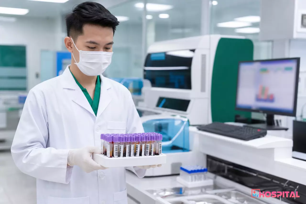 Kỹ thuật viên xét nghiệm cầm khay ống máu có nhãn mã vạch trong phòng xét nghiệm bệnh viện