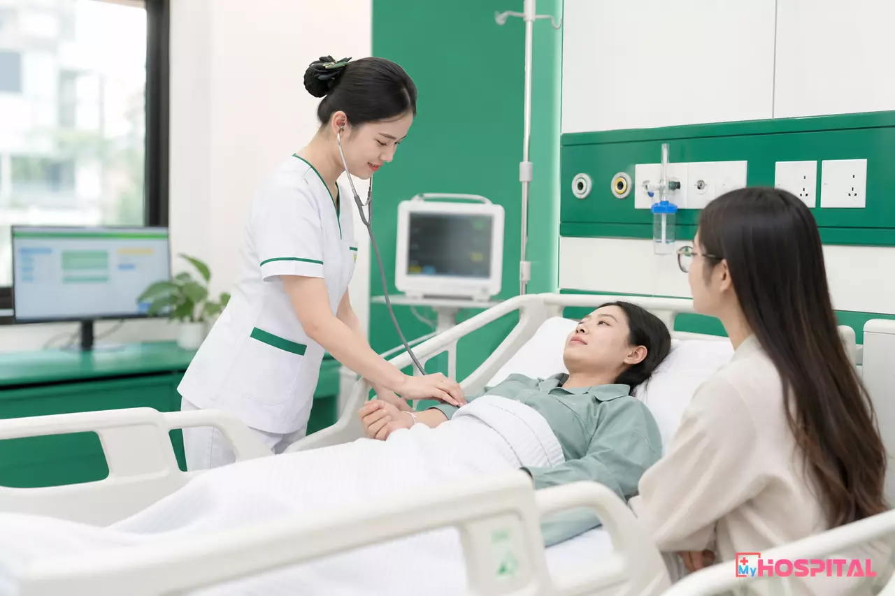 Điều dưỡng kiểm tra mạch và hỏi han người bệnh bên giường khi nhận bệnh mới