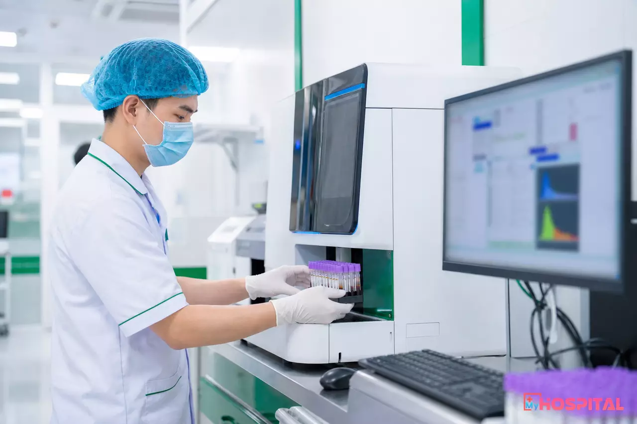 Kỹ thuật viên đặt giá ống máu vào máy phân tích kết nối với hệ thống LIS