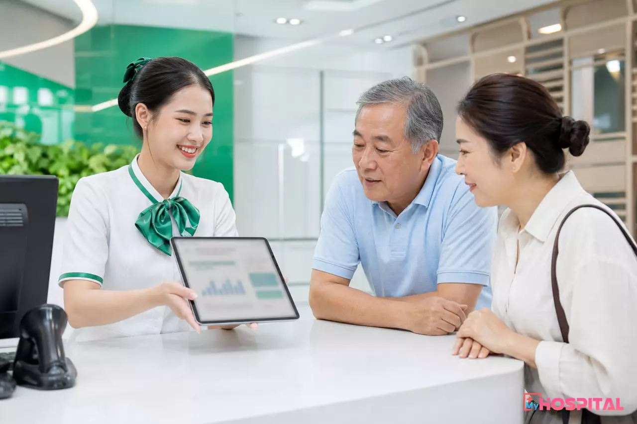 Nhân viên bộ phận tiếp đón hướng dẫn người bệnh xem kết quả chụp trên máy tính bảng