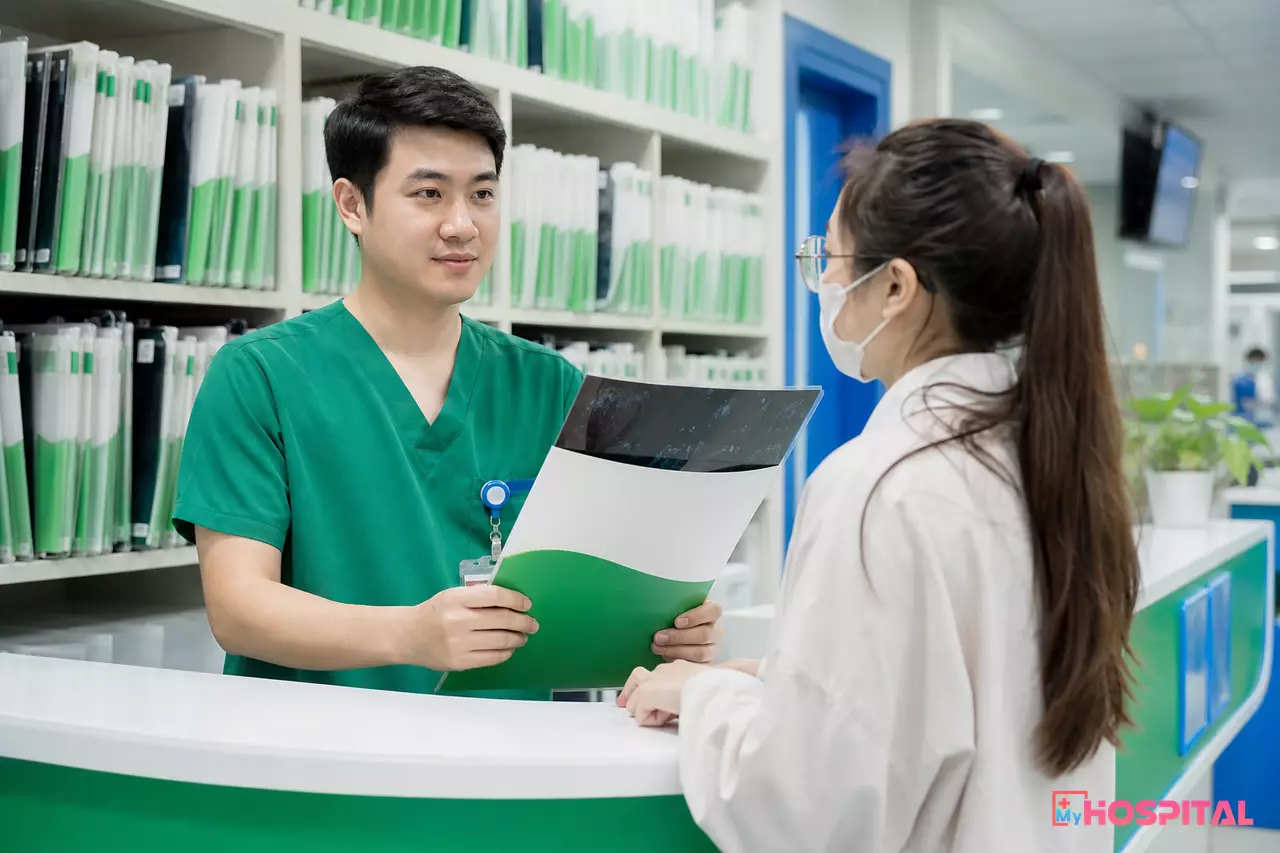 Kỹ thuật viên giữ tập phim X-quang nhựa tại quầy trả kết quả chẩn đoán hình ảnh