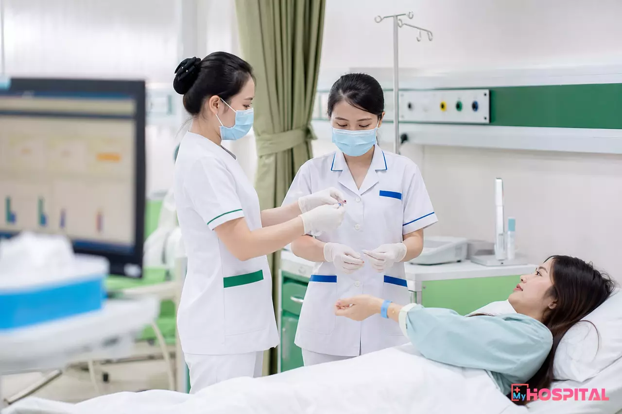 Hai điều dưỡng cùng đối chiếu thuốc và vòng đeo tay người bệnh trước khi tiêm