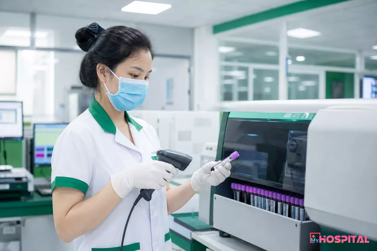 Kỹ thuật viên quét mã vạch ống máu trước khi đặt vào máy phân tích