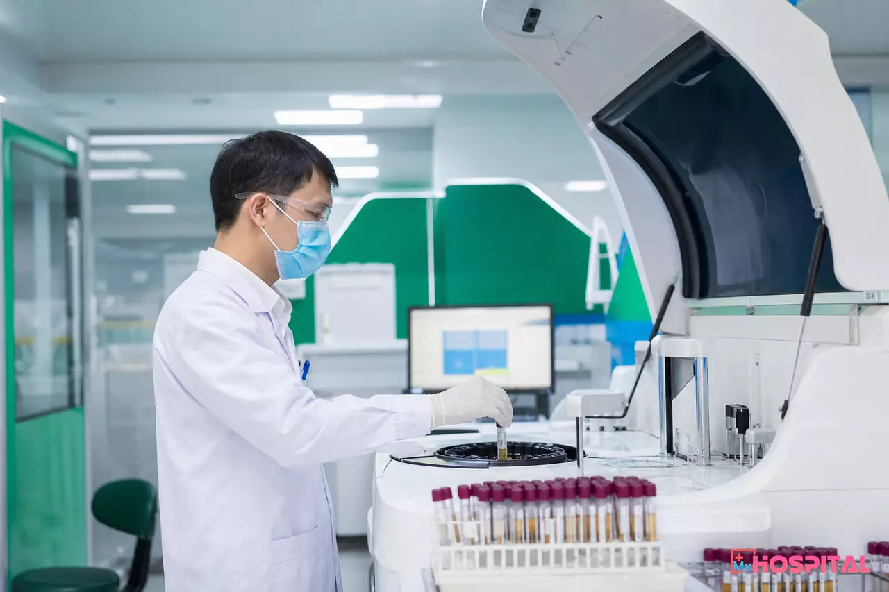 Kỹ thuật viên xét nghiệm thao tác máy phân tích sinh hóa tự động tại phòng xét nghiệm bệnh viện