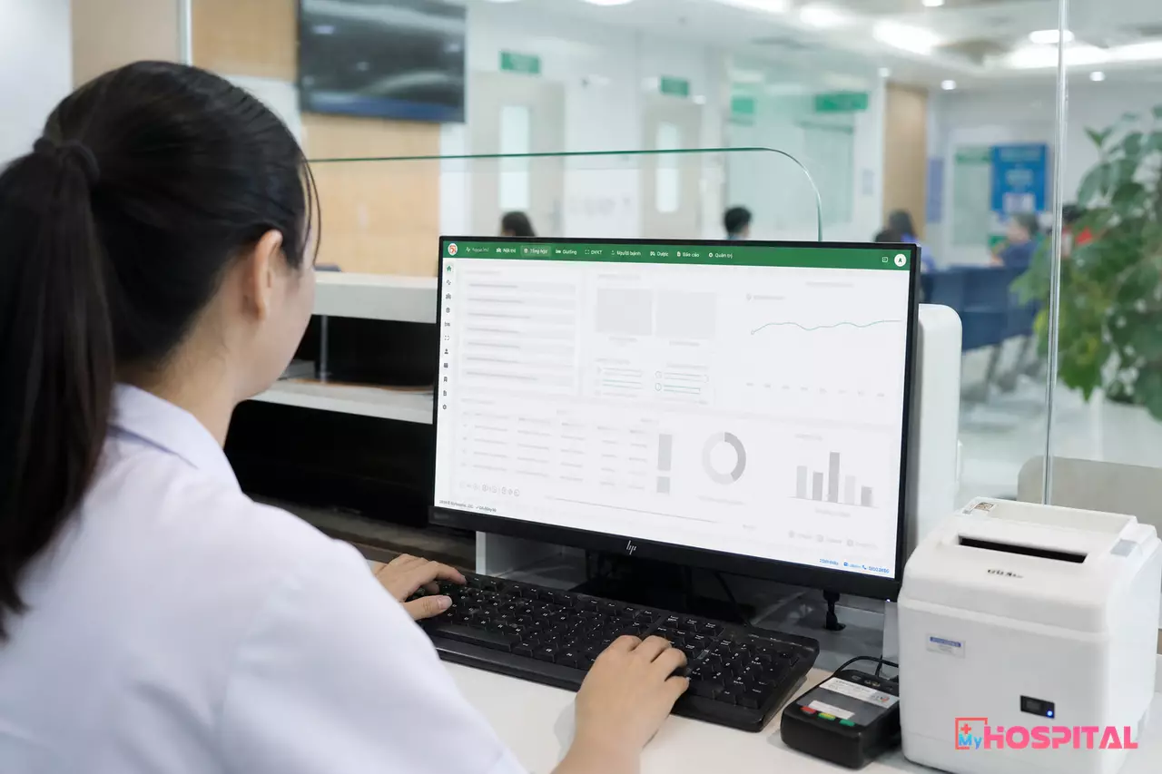 Thu ngân thao tác trên phần mềm quản lý bệnh viện, màn hình hiển thị bảng kê viện phí đã tự động điền mức hưởng BHYT