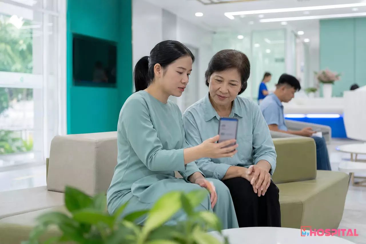Người nhà ngồi ở sảnh chờ bệnh viện cùng xem kết quả trên điện thoại