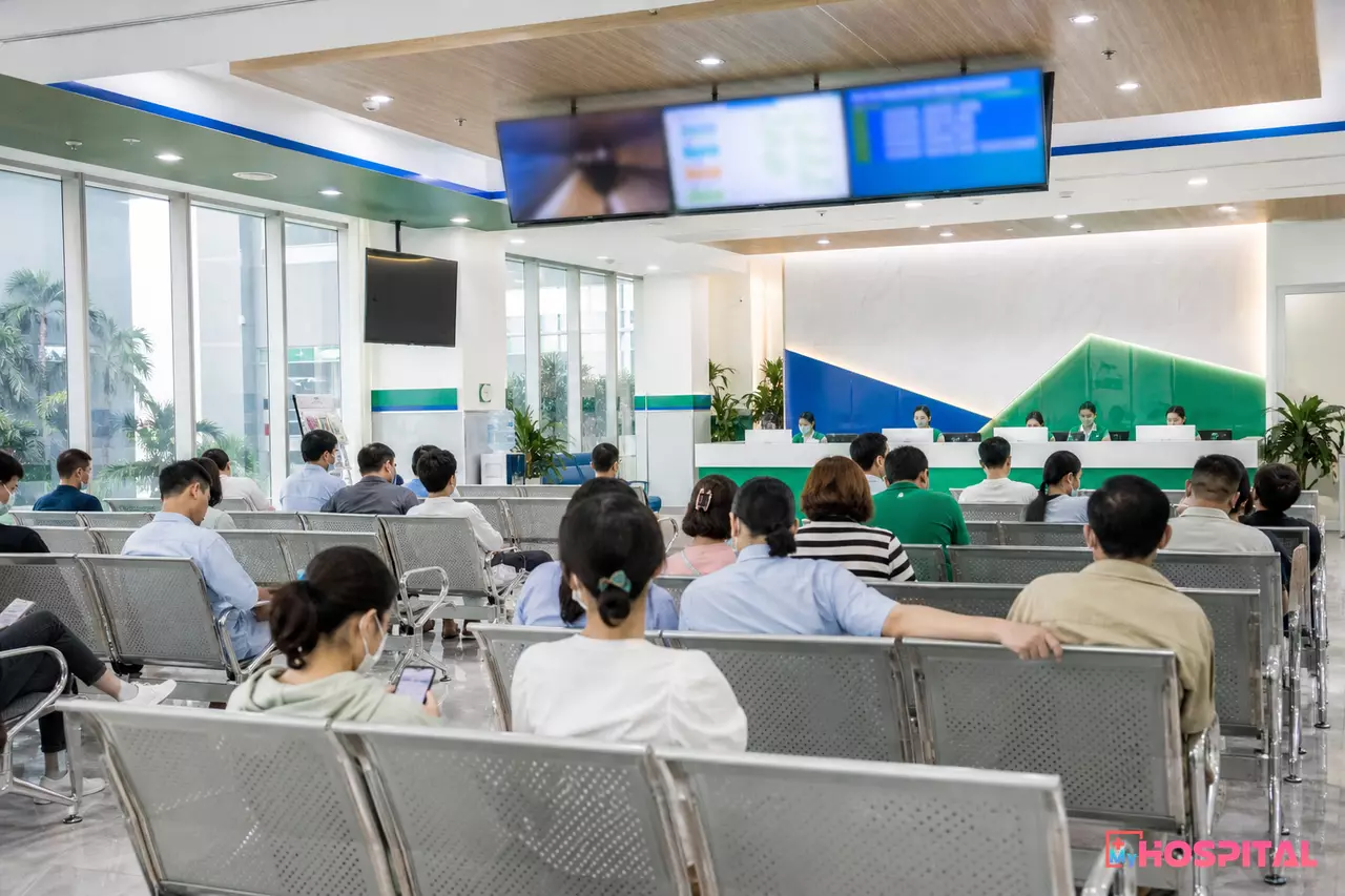 Sảnh chờ khám bệnh viện với bảng gọi số điện tử và người bệnh ngồi chờ