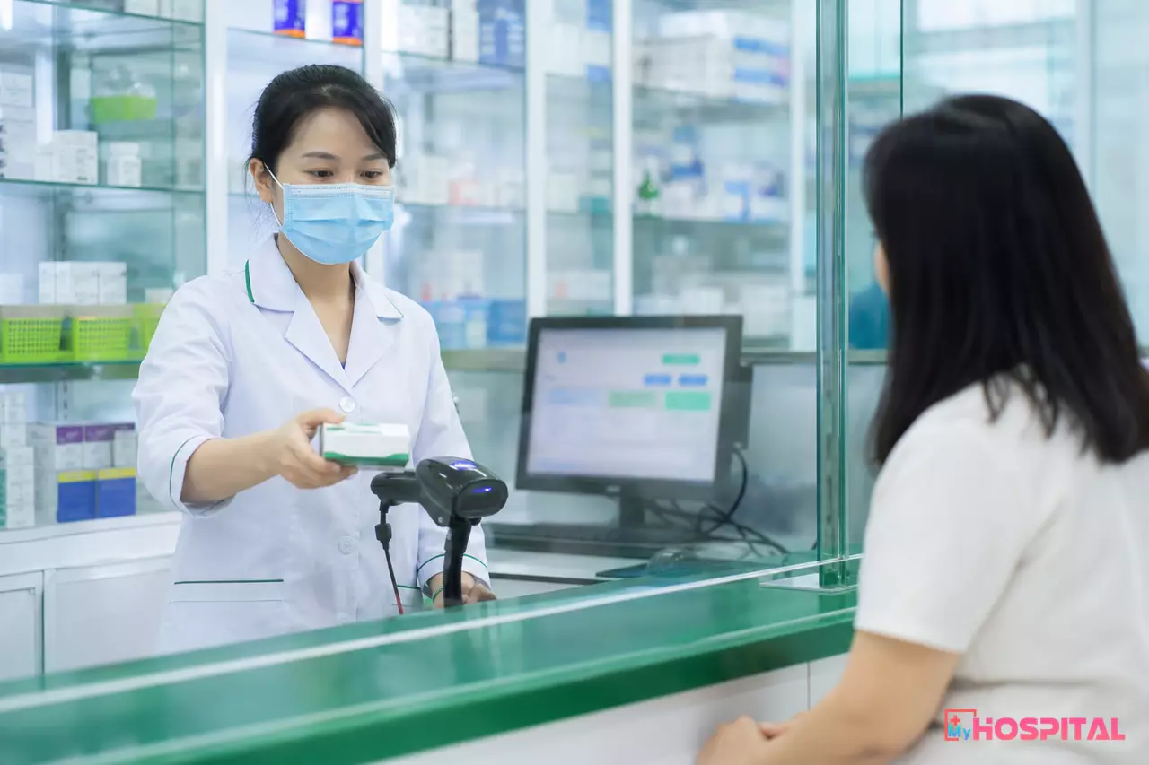 Dược sĩ quét mã QR trên vỏ hộp thuốc tại quầy thuốc bệnh viện trước khi giao cho người bệnh