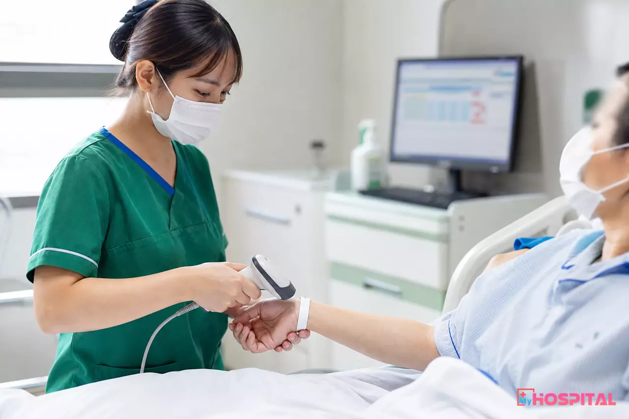 Điều dưỡng dùng máy quét kiểm tra vòng đeo tay có mã vạch trên cổ tay người bệnh nội trú